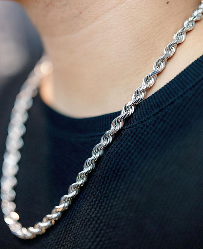 Silver rope chain necklace worn on a person with a dark shirt, emphasizing the necklace's elegant, interwoven design.