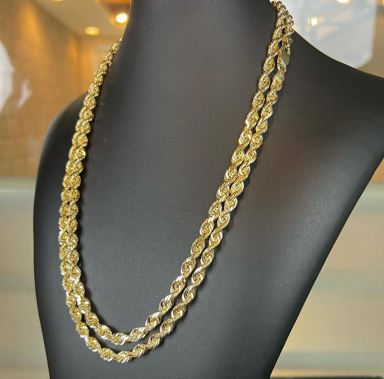 Double-layered gold rope chain necklace draped over a black mannequin, showcasing its luxurious, braided style.